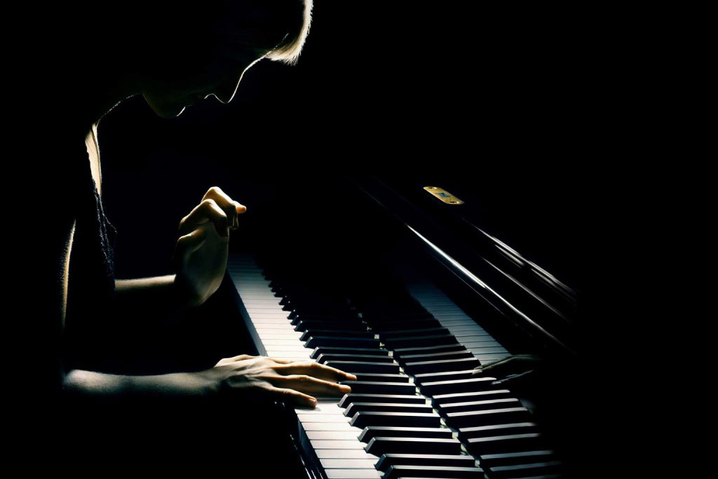 A woman is playing a piano in the dark.