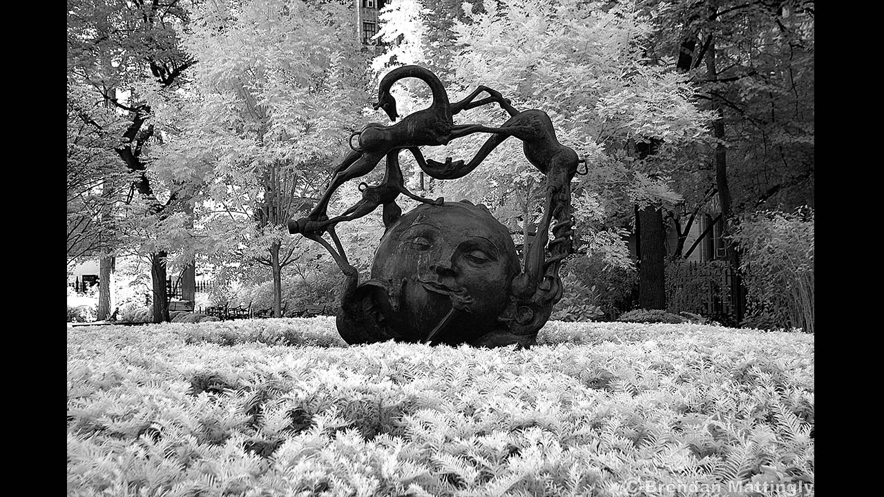 A black and white photo of a statue in a park.