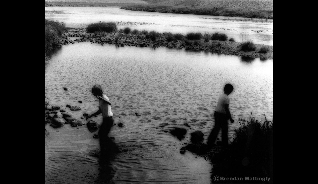A black and white photo of two people in a river.